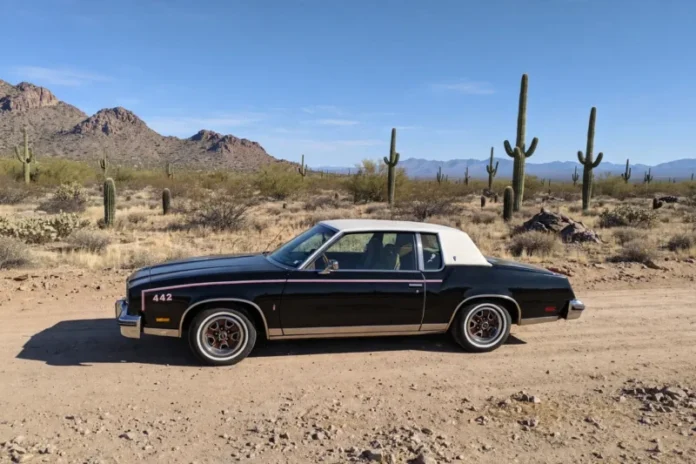 oldsmobile 442 crne boje i bijelim krovom parkiran u pustinji u teksasu na makadamskom putu
